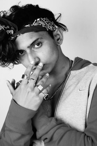 A grayscale of an Indian hipster guy with a headband posing to the camera - Fotó, kép