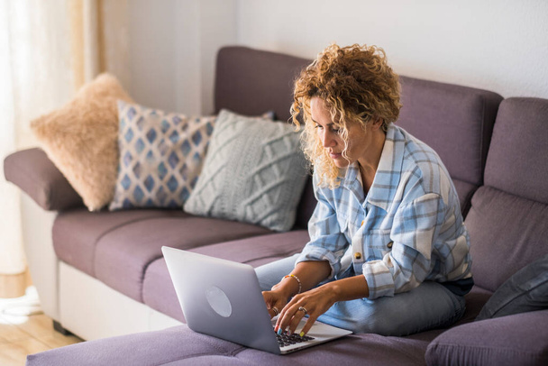 Moderne Frau legt sich auf die Couch und nutzt Laptop für die Arbeit oder surft im Internet - Foto, Bild