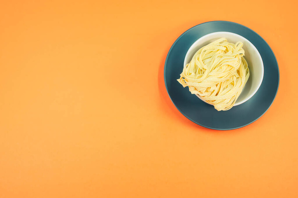 detail view of a bowl of cooked pasta on orange background with copy space - Фото, изображение