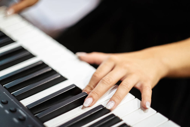 A closeup of female hands playing a digital piano - Foto, imagen