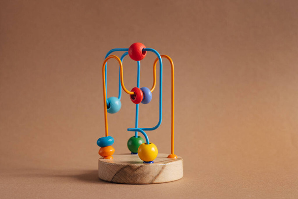 Developing toy for kids. The labyrinth of wooden beads on brown background - Zdjęcie, obraz