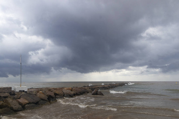 Plaża Benicssim-Benicsim i Morze Śródziemne łącząca się z wodą deszczową i powodziami wytwarzającymi mieszaninę osadów pozostawiających wodę brązową w Hiszpanii. W Europie. Fotografia pozioma. - Zdjęcie, obraz