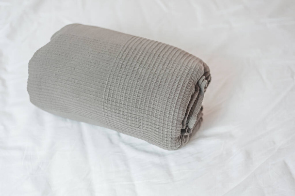 couverture de coton, roulé en rouleau, repose sur le lit sur une feuille blanche - Photo, image