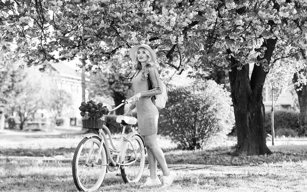 Active day. cherry tree pink blossom. perfect smell. perfume spa and allergic. travel. retro woman sell tulip flower bouquet. girl under sakura with vintage bicycle. spring beauty and fashion - Photo, image
