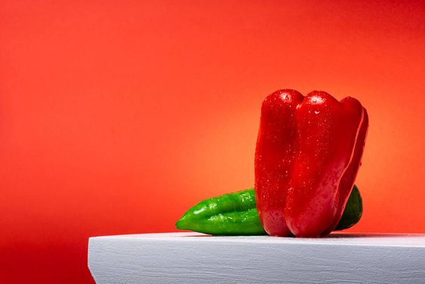 Fotografia di un peperone rosso e un peperone verde italiano su sfondo bianco e rosso.La foto è scattata in formato orizzontale e ha spazio per copiare. - Foto, immagini
