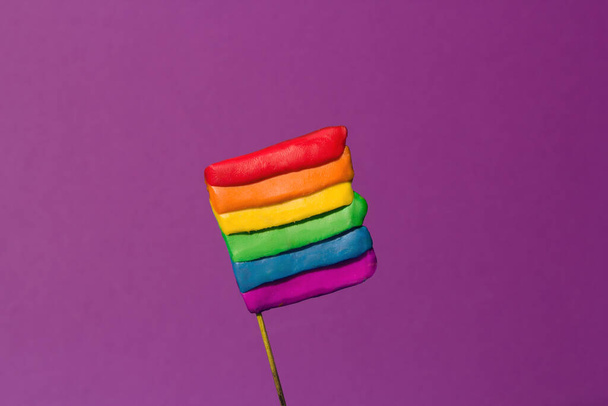 Bandera LGBT hecha por manos de plastilina sobre un fondo morado. Foto de alta calidad. - Foto, Imagen