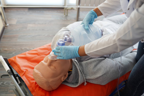 Studenci pielęgniarstwa ćwiczą, jak zapewnić pacjentowi podawanie tlenu przez lalkę pacjenta w symulacji wirtualnej obecności w szpitalu.. - Zdjęcie, obraz