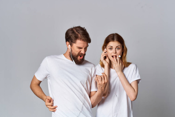 hombre y mujer con auriculares en las manos música fondo claro - Foto, Imagen