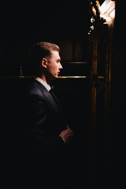 a man in a business suit in a dark room.  - Foto, Bild