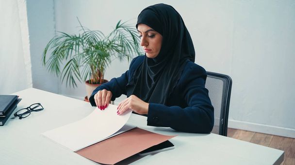 Muszlim üzletasszony hidzsábon, aki irodai dokumentumokkal dolgozik.  - Fotó, kép