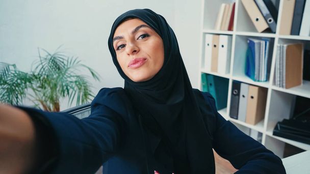 jeune femme d'affaires musulmane bouder les lèvres tout en prenant selfie  - Photo, image