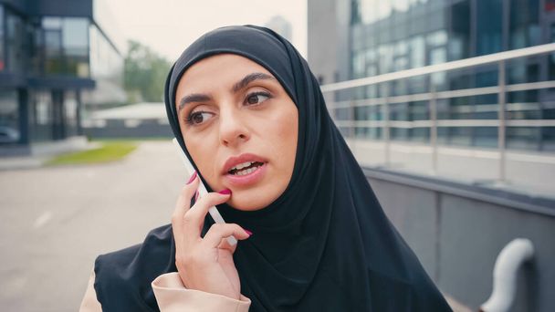 Молода арабська жінка в хіджабі має телефонний дзвінок зовні
 - Фото, зображення