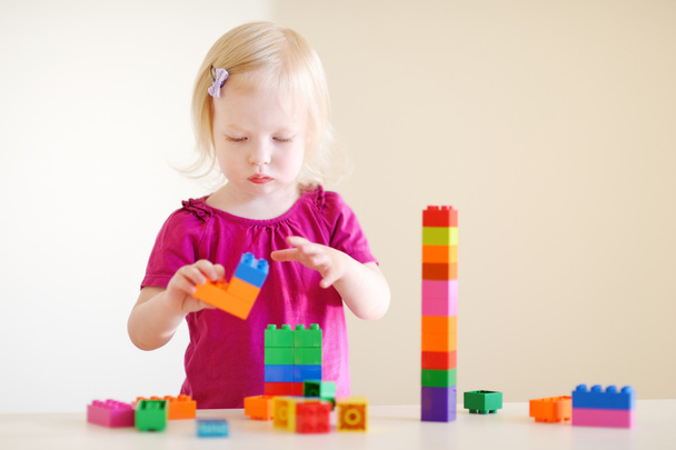 Girl playing with plastic blocks - Fotó, kép