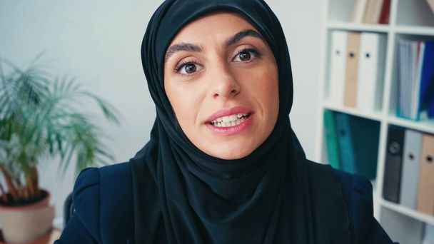 young muslim businesswoman in hijab talking while looking at camera - Zdjęcie, obraz