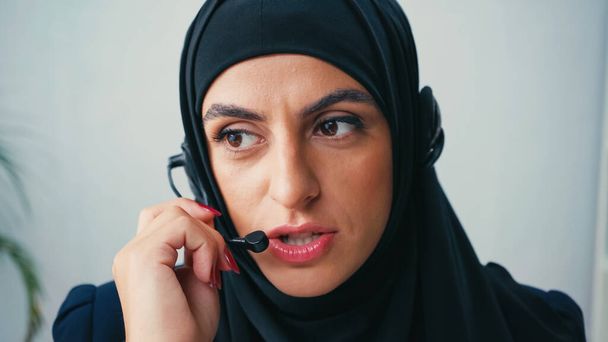 γυναίκα σε hijab χρησιμοποιώντας μικρόφωνο, ενώ μιλάμε στο τηλεφωνικό κέντρο  - Φωτογραφία, εικόνα