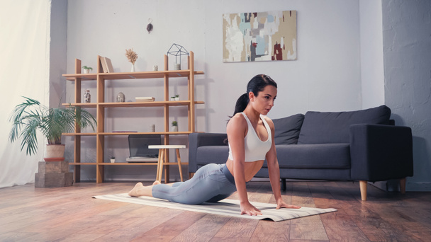 Barefoot sportswoman stretching on fitness mat at home  - Фото, зображення