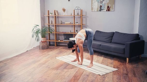 Ajuste deportista que se extiende de nuevo en la alfombra de fitness en casa  - Foto, Imagen