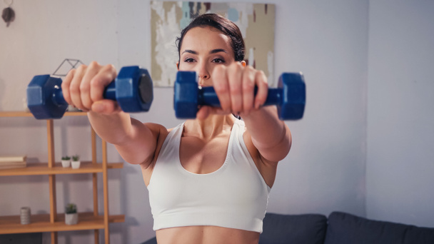 Sportswoman training with blurred dumbbells at home  - Zdjęcie, obraz