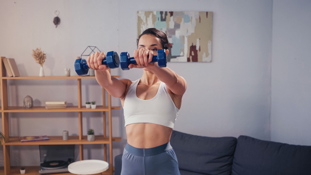 Fit sportswoman working out with dumbbells at home  - Photo, Image