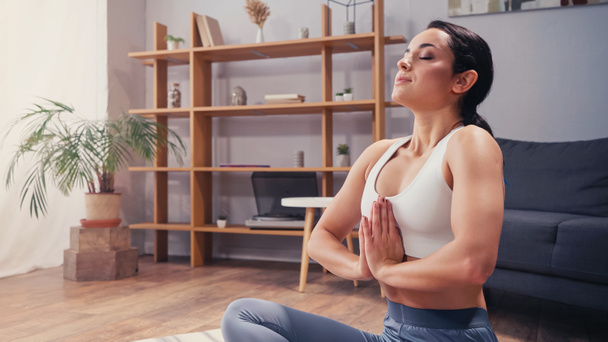Fit sportswoman meditating in living room  - Fotografie, Obrázek