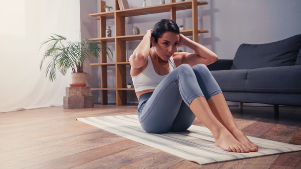 Sportlerin macht Bauch auf Fitnessmatte zu Hause  - Foto, Bild