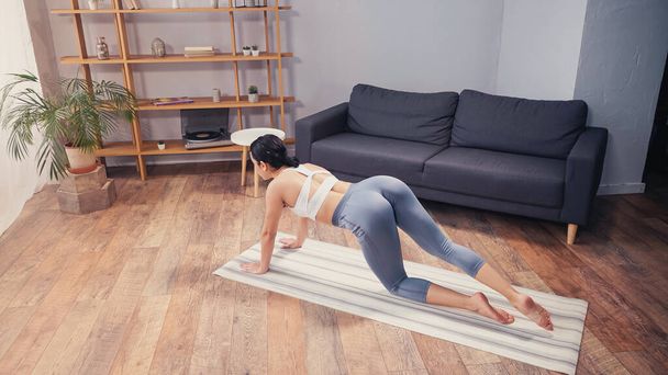Vysoký úhel pohledu na fit sportovkyně školení na fitness podložku doma  - Fotografie, Obrázek