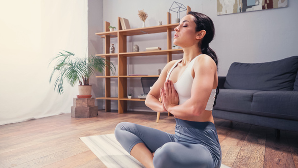 Vista lateral de una mujer bonita practicando yoga en casa  - Foto, imagen