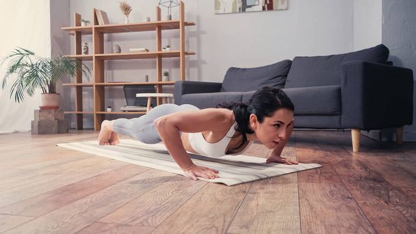 Kobieta robi wzloty prasy na macie fitness w domu  - Zdjęcie, obraz