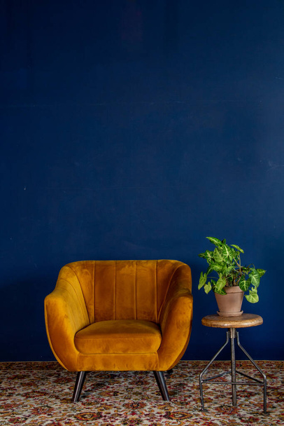 Elemento interior, sillón vacío amarillo contra fondo de pared azul, espacio para texto, espacio para copiar - Foto, Imagen
