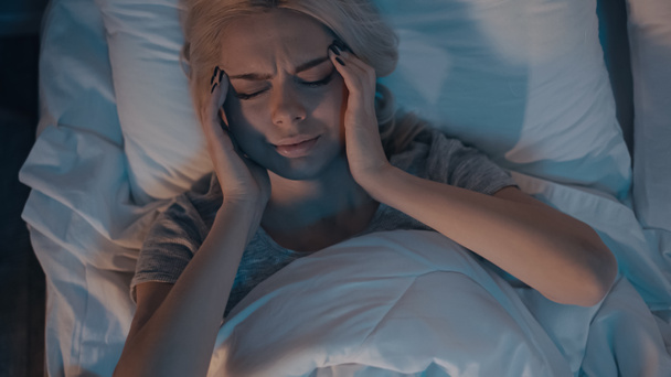 Top kilátás fiatal nő szenved fejfájás a hálószobában  - Fotó, kép