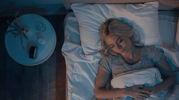 Top view of woman sleeping near alarm clock and pills in bedroom  - Foto, imagen