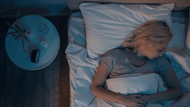 Top view of sick woman sleeping near pills and water in bedroom  - Foto, Imagen