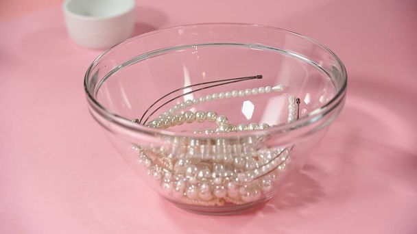 hairbands with pearls in glass bowl on pink - Zdjęcie, obraz