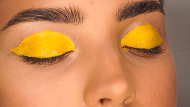 partial view of woman applying yellow creamy eye shadow with cosmetic brush - Valokuva, kuva