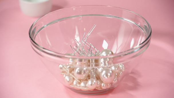 haarspelden met parels in glazen schaal op roze - Foto, afbeelding