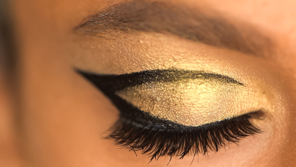 cropped view of african american woman with eye liner and golden eye shadow - Foto, Imagen