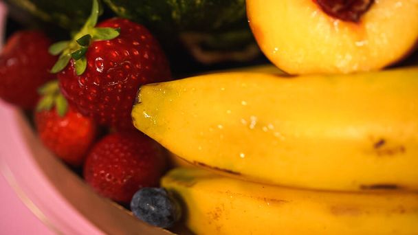 Nahaufnahme reifer Bananen bei roten Erdbeeren und Pfirsich - Foto, Bild