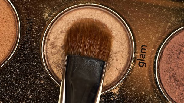 vista superior de escova cosmética perto de sombra de olho marrom com glam lettering - Foto, Imagem