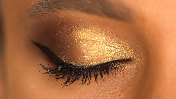 cropped view of african american woman with closed eye and golden eye shadow - Foto, Imagen