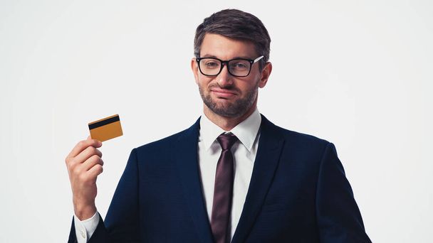 Usmívající se podnikatel držící kreditní kartu a dívající se na kameru izolované na bílém - Fotografie, Obrázek