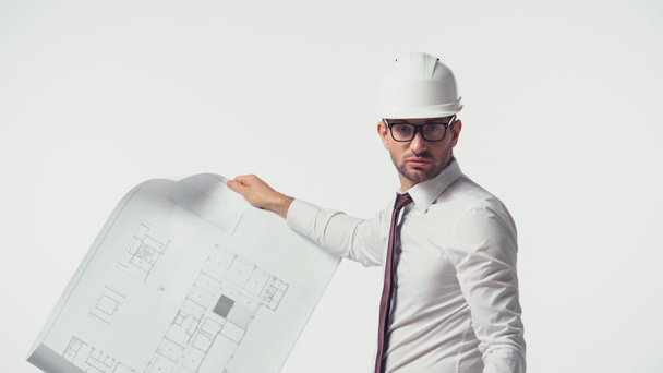 Architect in hardhat holding blueprint and looking at camera isolated on white - Fotó, kép