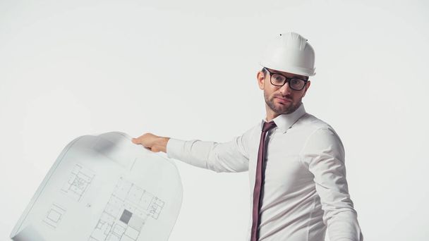 Engineer in hardhat holding blurred blueprint isolated on white - Фото, изображение