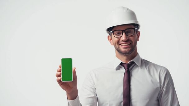 Engineer in hardhat holding smartphone with chroma key isolated on white - Фото, изображение