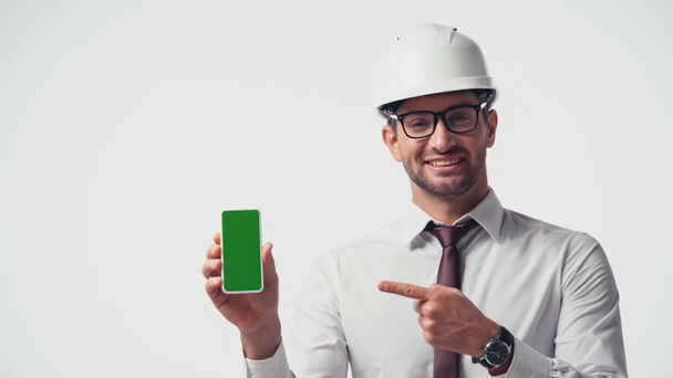 Architect in helmet pointing at mobile phone with chroma key isolated on white - Photo, Image
