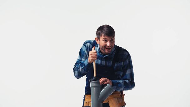 Usmívající se dělník s pístem a plastovou trubkou izolovanou na bílém - Fotografie, Obrázek