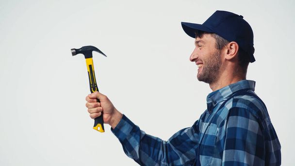 Side view of cheerful workman holding hammer isolated on white - Foto, afbeelding