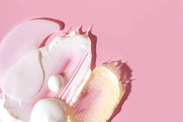 Various cosmetic mask, creams, serum, scrub and lotion smear on a pink background. Beauty texture. Sample of a cosmetic product. - Foto, Imagen