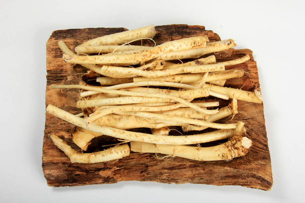 Cortar raízes de rábano (Armoracia rusticana taproot) em tábua de madeira rústica. Rábano fresco. - Foto, Imagem