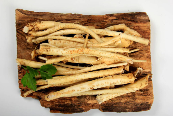 Cut Horseradish roots (Armoracia rusticana taproot) on rustic wooden board. Fresh horseradish. - Photo, Image