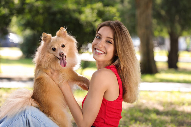 Young woman with her cute dog in park on sunny day - Φωτογραφία, εικόνα